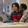 Two students sitting side by side behind a computer submitting a form to learn more about Global Programs