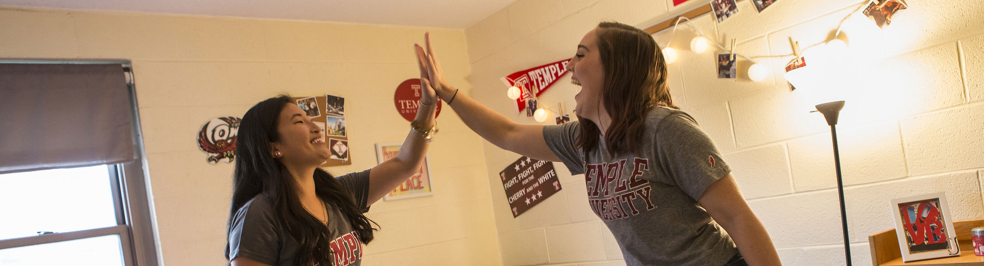 Two female students high-fiving in their on-campus residence hall