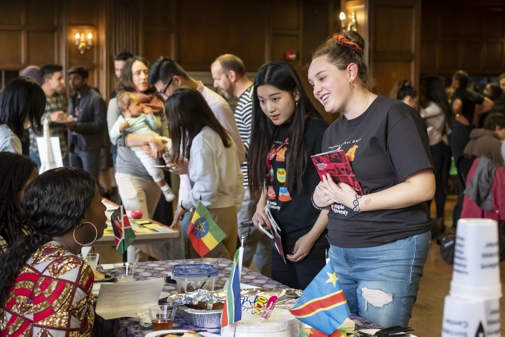 Two female students talking to a student at a student organization table at Global Gala event