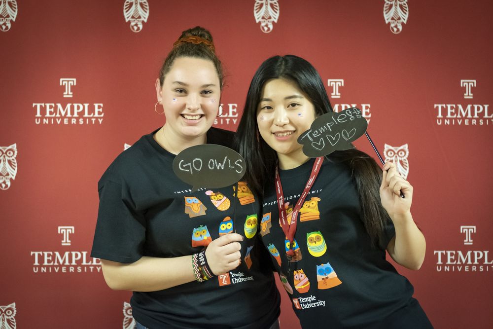 Two female students holding up "Temple" and "Go Owls" signs at orientation